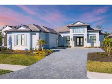 Two-story home with a gray tile roof, white walls, and a paver driveway at 10628 Nicklaus Ct, Englewood, FL 34223