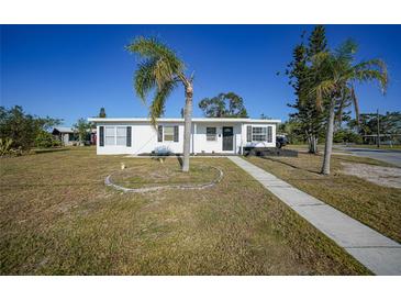 White single story home with palm trees and landscaped lawn at 230 Waterway Ne Cir, Port Charlotte, FL 33952