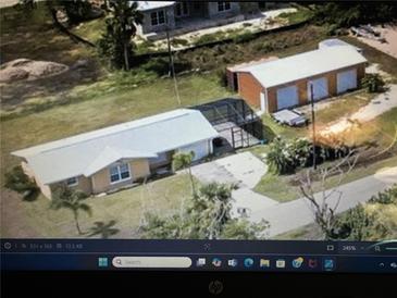 Aerial view showing a single-story home, detached garage, and fenced backyard at 2727 Poinciana Ct, Punta Gorda, FL 33950