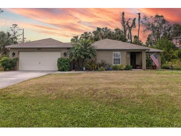 Single-story home with attached garage, landscaped lawn, and American flag at 3953 Vehlin St, North Port, FL 34286