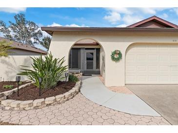 Inviting exterior with landscaped walkway leading to a covered entryway and attached garage at 616 Cherrywood Dr, Englewood, FL 34223