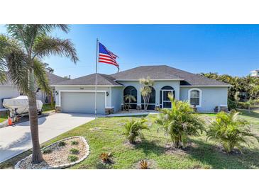 Single-story home with attached garage, landscaping, and American flag at 7083 Mifflin St, Englewood, FL 34224