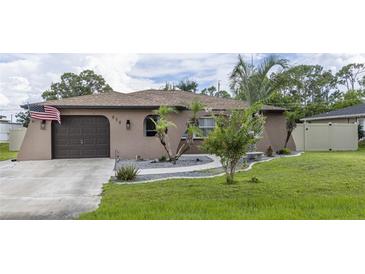 House exterior featuring a one-story home with a brown garage door and landscaped yard at 939 Silver Springs Nw Ter, Port Charlotte, FL 33948