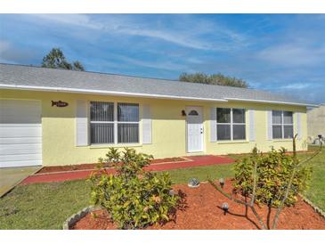Cute yellow house with well-manicured landscaping and a spacious front yard at 13366 Bronze Ave, Port Charlotte, FL 33981