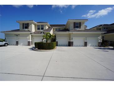 Tan three-story building with attached garages and lush landscaping at 17074 Acapulco Rd # 112, Punta Gorda, FL 33955