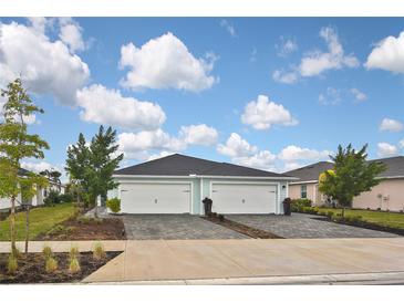 Two-car garage, light teal exterior, and landscaped yard at 17764 Palmetto Pass Ln, Punta Gorda, FL 33982
