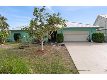 Charming light teal house with metal roof, two-car garage, and landscaped yard at 1845 Edison Dr, Englewood, FL 34224