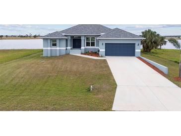 One-story home with gray siding, attached garage, and landscaped yard at 27 Meadowlark Ln, Placida, FL 33946