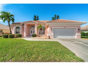 Pink one-story home with a two-car garage and landscaped lawn at 632 Balsam Apple Dr, Venice, FL 34293