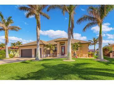 Tan house with brown garage doors, landscaping, and palm trees at 1002 Messina Dr, Punta Gorda, FL 33950