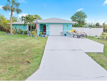 Light teal house with a two-car garage and a long driveway, plus a jet ski on a trailer at 1638 Viscaya Dr, Port Charlotte, FL 33952