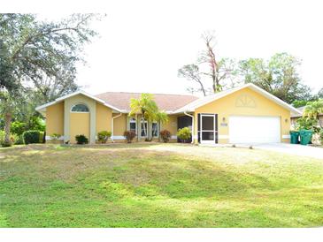 Attractive yellow house with a well-maintained lawn and landscaping at 21217 Knollwood Ave, Port Charlotte, FL 33952