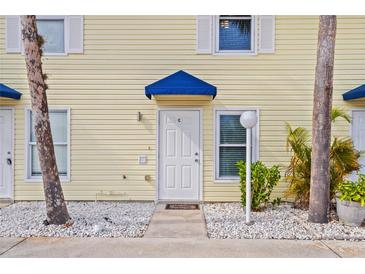 Exterior view of a light yellow building with a blue awning and white door at 26346 Rampart Blvd # 904, Punta Gorda, FL 33983