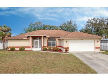 Tan house with brown roof, white garage door, and landscaped yard at 4046 Lubec Ave, North Port, FL 34287