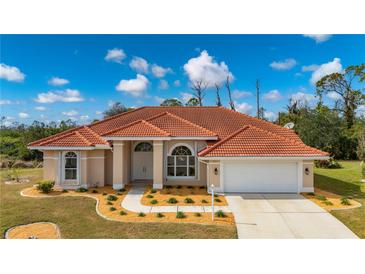 Single-story home with tile roof, landscaped yard, and attached garage at 8326 Creekview Ln, Englewood, FL 34224