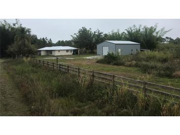 Aerial view of a house and detached garage on a large lot with fenced area at 15570 Rasmussen Rd, Punta Gorda, FL 33982