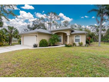 Tan house with a two-car garage and lush lawn at 4522 Mckay St, North Port, FL 34286