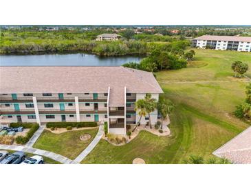Aerial view of condo building, tennis courts, pool, and surrounding landscape at 175 Kings Hwy # 528, Punta Gorda, FL 33983