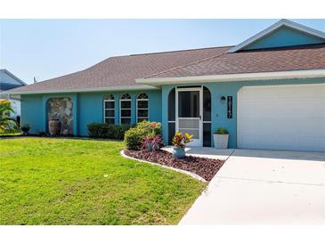 Front view of a charming teal home with well-maintained landscaping at 18147 Cadillac Ave, Port Charlotte, FL 33948