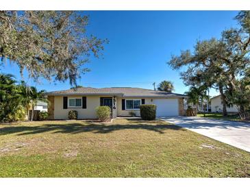Inviting ranch-style home with a well-manicured lawn and mature trees at 514 Orlando Blvd, Port Charlotte, FL 33954