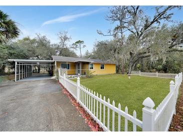 Cute yellow house with carport, white picket fence, and well-manicured lawn at 103 Atwater St, Port Charlotte, FL 33954