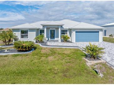 Single-story home with metal roof, paver driveway, and landscaping at 14303 Maysville Cir, Port Charlotte, FL 33981