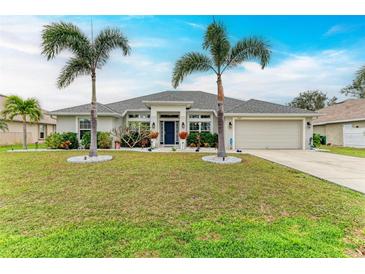 Single-story home with a landscaped lawn, palm trees, and a two-car garage at 2467 Odessa Ln, Punta Gorda, FL 33983