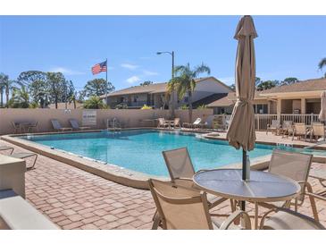 Community pool with lounge chairs and patio tables at 2763 Woodgate Ln # 206, Sarasota, FL 34231