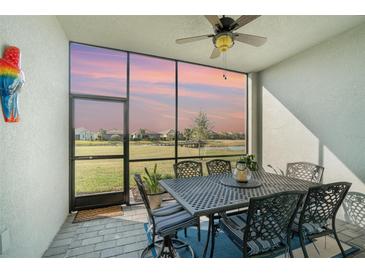 A covered outdoor dining area features decorative table and chairs with views of a sunset over the pond at 43996 Boardwalk Loop # 1411, Punta Gorda, FL 33982