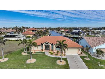 Aerial view of waterfront home with canal access, lush landscaping, and nearby residences at 720 Bimini Ln, Punta Gorda, FL 33950