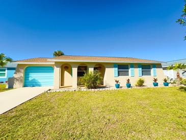 Tan house with blue shutters, garage door, and well-manicured lawn at 1063 Elaine St, Venice, FL 34285