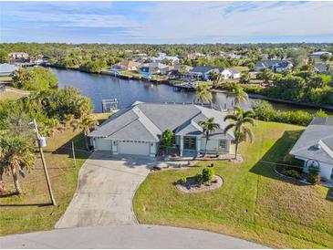 Aerial view of waterfront home with canal access, lush landscaping, and a two-car garage at 17456 Foremost Ln, Port Charlotte, FL 33948