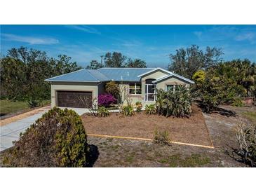 Single-story house with metal roof, attached garage, and landscaped yard at 24362 Yacht Club Blvd, Punta Gorda, FL 33955