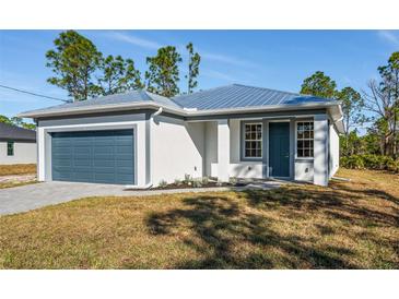 One-story home with metal roof, attached garage, and landscaped lawn at 27066 Sumatra Dr, Punta Gorda, FL 33955
