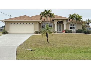 Tan house with brown roof, palm trees, and a grassy yard at 273 Mark Twain Ln, Rotonda West, FL 33947