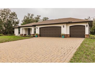 Three-car garage, paver driveway, and landscaped front yard at 3495 Levee St, North Port, FL 34288