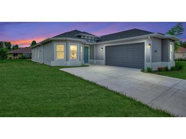 One-story home with gray exterior, two-car garage, and a well-manicured lawn at 4629 Enid Ln, North Port, FL 34288