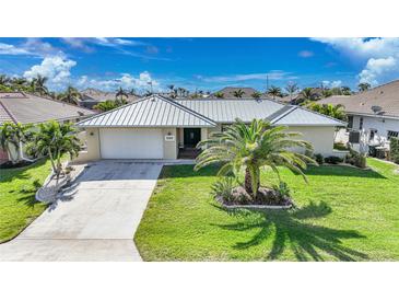 Single-story home with metal roof, palm tree, and driveway at 1029 San Mateo Dr, Punta Gorda, FL 33950