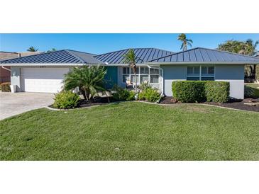 Single-story home with a metal roof, landscaping, and a paved driveway at 2871 Coral Way, Punta Gorda, FL 33950