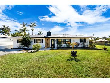 Newly renovated home with a modern exterior, featuring a metal roof and landscaped lawn at 3429 Sleepy Hollow Ln, Punta Gorda, FL 33950