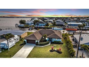 Waterfront home boasts lush landscaping, boat dock, and stunning sunset views over the water at 5194 Fleming St, Port Charlotte, FL 33981