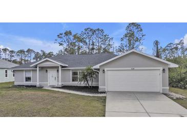 Well-maintained single-Gathering home featuring a two-car garage, landscaped front yard, and inviting entryway at 1230 Gantry Rd, North Port, FL 34288