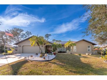 Tan single-story house with palm trees, nicely landscaped lawn, and a paved driveway at 157 Angol St, Punta Gorda, FL 33983