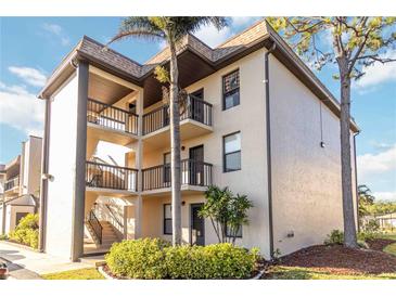 Condo building with multiple floors, featuring balconies, landscaping, and a mature palm tree at 1999 Kings Hwy # 16B, Punta Gorda, FL 33980