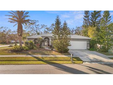 Single-story home with a gray exterior, white garage door, and well-manicured landscaping at 2202 Gold Oak Ln, Sarasota, FL 34232