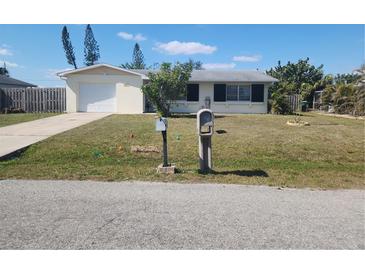 Charming single-story home featuring a well-manicured lawn and attached garage with a classic mailbox in the front yard at 2461 Ivanhoe St, Port Charlotte, FL 33952