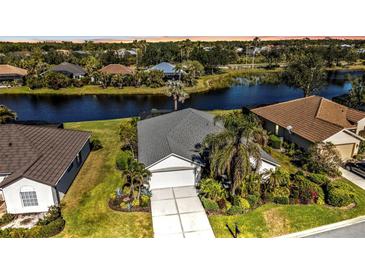 Single-Gathering home with grey roof, white garage door, and lush landscaping near water at 3380 Bay Ridge Way, Port Charlotte, FL 33953