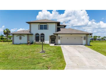 Two-story house with a beige exterior, two-car garage, and lush green lawn at 4630 Fallon Cir, Port Charlotte, FL 33948