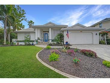 White one-story home with landscaped yard, blue door, and two-car garage at 5028 San Massimo Dr, Punta Gorda, FL 33950