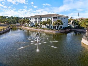 Aerial view of condo building with lake, fountain, and lush landscaping at 700 Gardens Edge Dr # 722, Venice, FL 34285